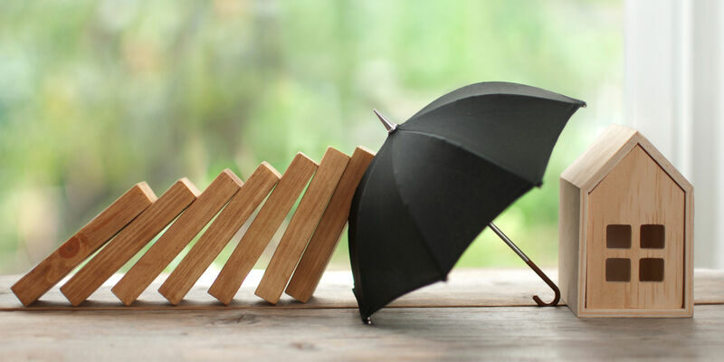Umbrella protecting house from domino collapse, insurance concept