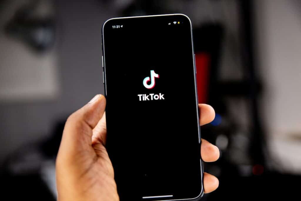 Smartphone in a hand displaying the TikTok logo on a black screen